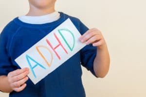 young boy with sign reading adhd